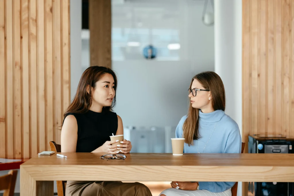 Two women talking over coffee in a modern office